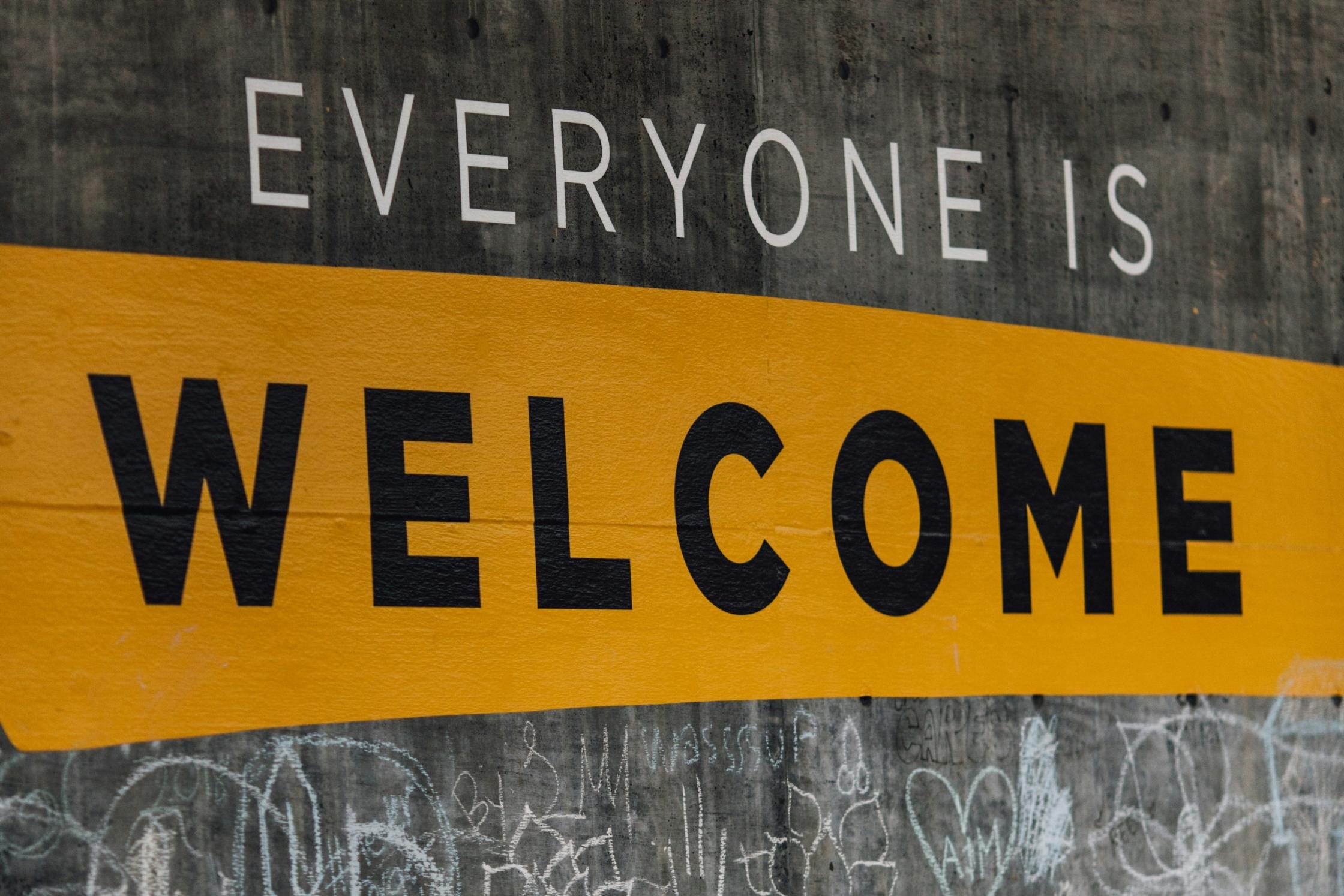 Ein gelbes Willkommensschild auf grauem Untergrund